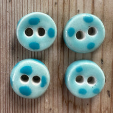 Load image into Gallery viewer, Four light blue buttons with darker blue spots on a wooden surface