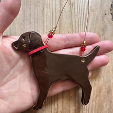 Load image into Gallery viewer, Brown dog-shaped decoration held in a hand on a wooden surface