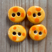 Load image into Gallery viewer, Four orange ceramic buttons with orange dots on a wooden surface