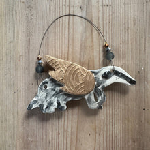 Load image into Gallery viewer, Decorative badger wall hanging with gold wings on a wooden surface
