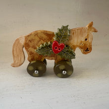 Load image into Gallery viewer, Decorative horse figurine with holly leaves and a red berry on wheels against a plain background