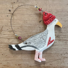 Load image into Gallery viewer, Decorative ceramic seagull in a bobble hat on a wooden surface