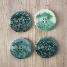 Load image into Gallery viewer, Four green ceramic buttons with a landscape design on a wooden surface