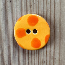 Load image into Gallery viewer, Round orange button with two holes on a wooden surface