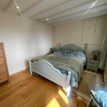 Load image into Gallery viewer, Bedroom with wooden drawers, bed, and 2 windows with curtains and blinds.