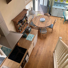 Load image into Gallery viewer, Kitchen with wooden dining table and chairs, and a staircase in the foreground.