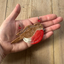 Load image into Gallery viewer, Hand holding a decorative robin ornament with a red heart on a wooden surface