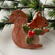 Load image into Gallery viewer, A hand-cut clay squirrel decoration with a red heart, glazed and strung on wire, featuring green and red glass beads.