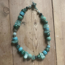 Load image into Gallery viewer, Necklace with sea green and turquoise beads on a wooden surface
