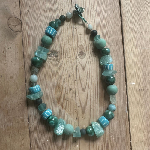 Necklace with sea green and turquoise beads on a wooden surface