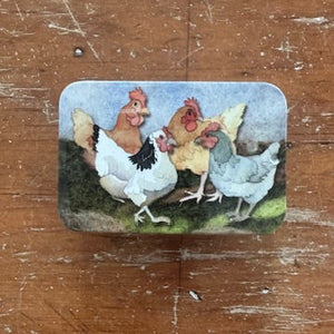 Decorative tin with cartoon-style chickens on a wooden surface