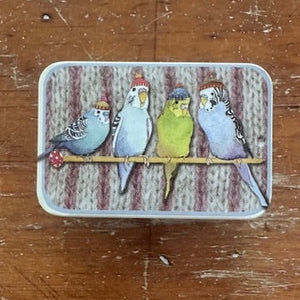 Rectangular tin with illustrations of four budgies in beanies on a wooden surface