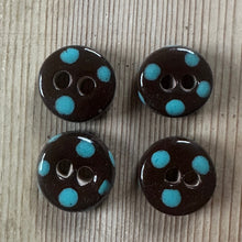 Load image into Gallery viewer, Four chocolate ceramic buttons with blue polka dots on a textured wooden background
