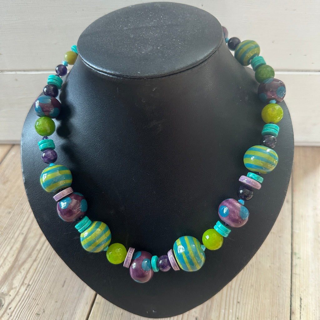 Colourful beaded necklace on a black bust against a wooden background