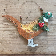Load image into Gallery viewer, Decorative wall hanging of a pheasant with holly leaves and berries on a wooden surface
