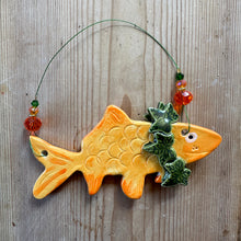 Load image into Gallery viewer, Decorative ceramic goldfish with a n ivy wreath on a wooden surface

