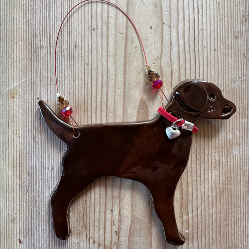 Brown dog-shaped decoration with a red collar on a textured surface