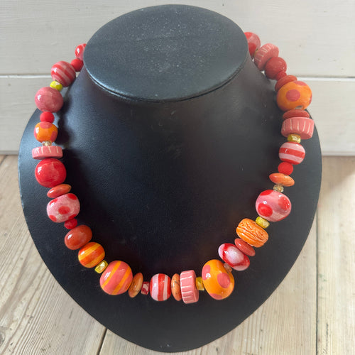 Black bust with colourful bead necklace on a wooden surface