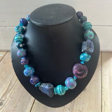 Load image into Gallery viewer, Multi-coloured beaded necklace on a black bust stand against a wooden background
