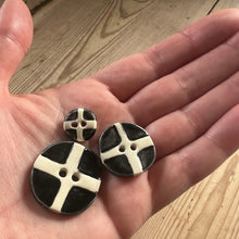 Load image into Gallery viewer, Three black and white buttons held in a hand on a wooden surface
