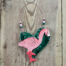 Load image into Gallery viewer, Pink and green flamingo-shaped decoration on a wooden surface
