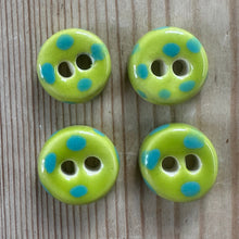 Load image into Gallery viewer, Four green buttons with blue polka dots on a wooden surface
