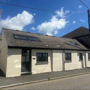 Single-story building with a sloped roof and Velux windows under a blue sky.