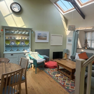 Living room with a staircase, dining table, and various furniture pieces.