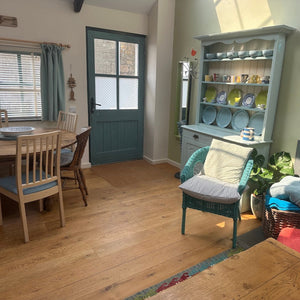 Living room with wooden floor, dining table, and shelves with decorative items.