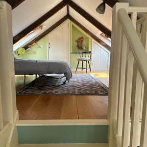 Staircase leading to a mezzanine with wooden floor and green walls.