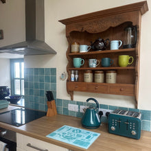 Load image into Gallery viewer, Kitchen counter with wooden shelf, teal kettle, toaster, and various items.
