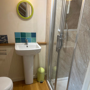 Bathroom with toilet, sink, and shower cubicle.