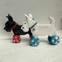 Load image into Gallery viewer, Two ceramic dogs on wheels against a light  background
