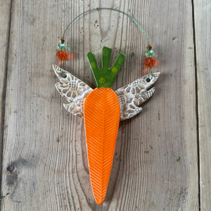 Decorative carrot with gold wings on a wooden surface