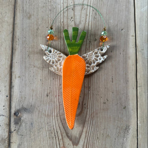 Decorative carrot with lace wings on a wooden surface