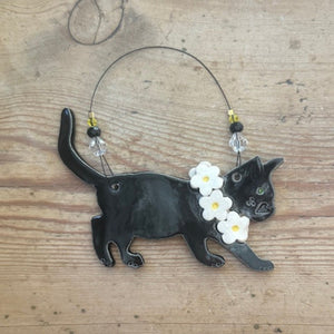 Black cat-shaped ornament with flowers on a wooden surface