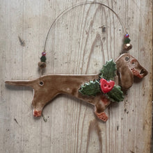Load image into Gallery viewer, Ceramic dachshund ornament with holly and berries on a wooden surface

