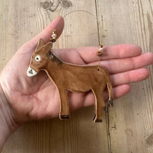Load image into Gallery viewer, Hand holding a brown donkey ornament on a wooden surface
