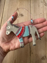 Load image into Gallery viewer, Hand holding a decorative donkey ornament with colourful patterned jumper on a wooden surface
