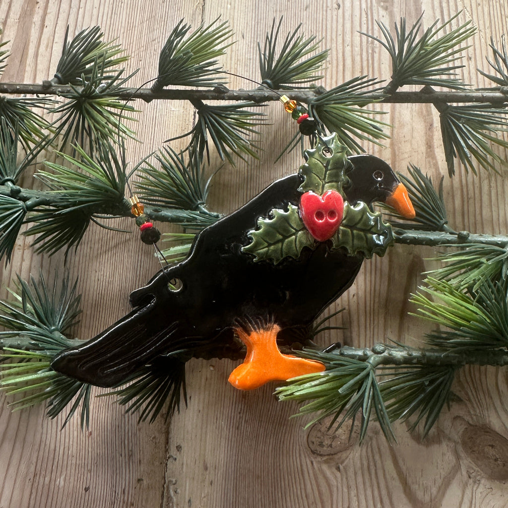 Decorative chough bird with  hollya nd green branches on a wooden surface