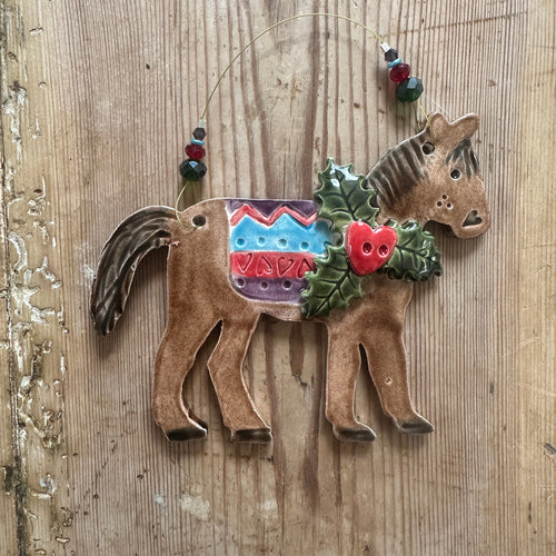 Decorative horse figure with colourful saddle on a wooden surface