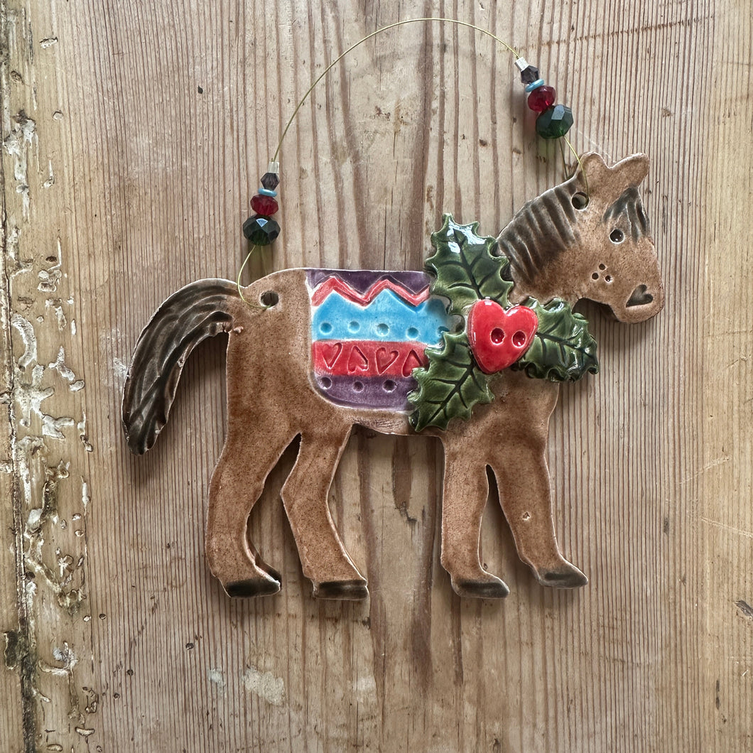 Decorative horse figure with colourful saddle on a wooden surface