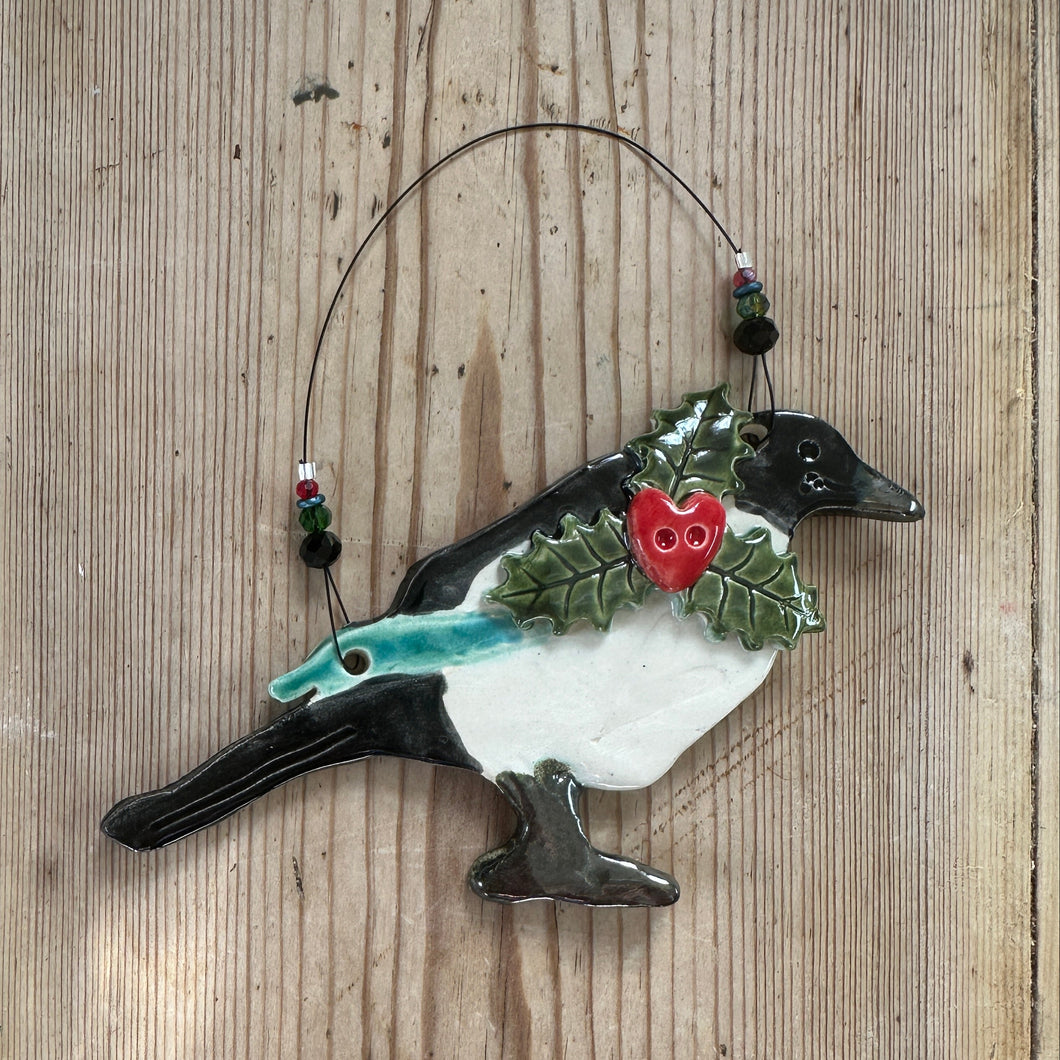 Decorative magpie ornament with holly on a wooden surface