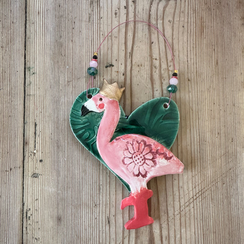 Decorative ceramic flamingo with floral design on a wooden surface