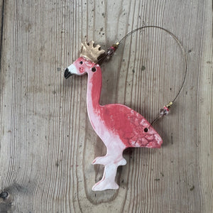 Pink flamingo ornament with a gold crown on a wooden surface