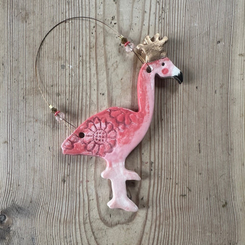 Decorative pink flamingo ornament with a gold crown on a wooden surface
