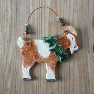 Decorative goat ornament with green leaves on a wooden surface