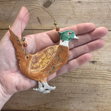 Load image into Gallery viewer, Hand holding a decorative bird ornament against a wooden background
