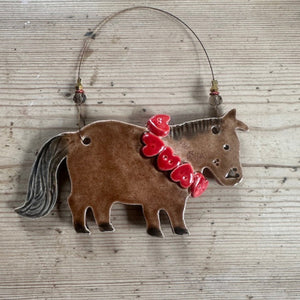 Decorative horse ornament with a red hearts on a wooden surface