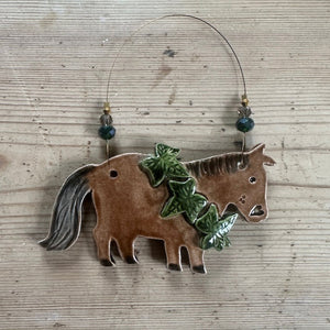 Decorative pony-shaped ornament with ivy on a wooden surface